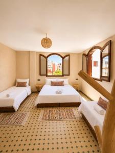 two beds in a room with two windows at Kymata Surf Morocco in Agadir