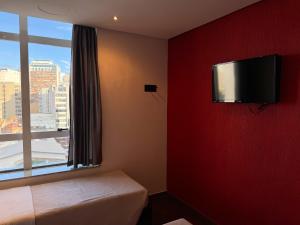 a room with a red wall with a flat screen tv at Center Verdes Pássaros Loft in Porto Alegre