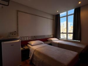 a hotel room with two beds and a window at Center Verdes Pássaros Loft in Porto Alegre