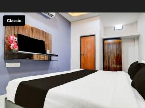 a bedroom with a white bed and a tv at Kanakplace in Indore