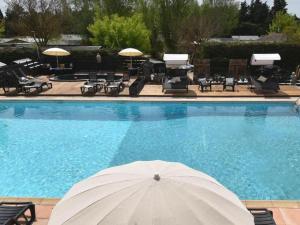a large swimming pool with a white umbrella in front of it at Chalet clim, TV - 2 pers. - API-1-52-2795 in Noves