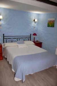 1 dormitorio con 1 cama blanca grande y pared azul en Casa Angel, en Sequeros