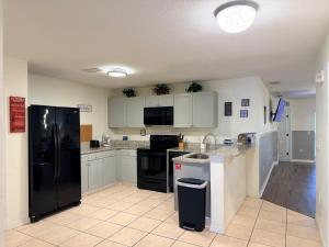 a kitchen with black appliances and white cabinets at Disney Kissimmee Condo in Kissimmee