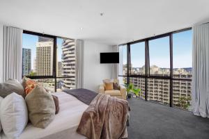 a bedroom with a large bed and large windows at Aria Apartments in Gold Coast