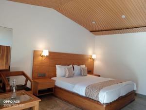 a bedroom with a large bed and a table at Serene Forest Resort in Nainital +49 photos