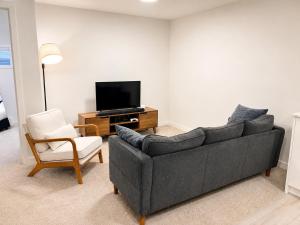 a living room with a couch and a tv and a chair at Modern 2BR Private Suite in SW Calgary in Calgary