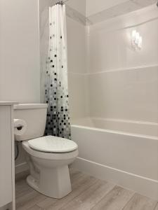 a white bathroom with a toilet and a bath tub at Modern 2BR Private Suite in SW Calgary in Calgary