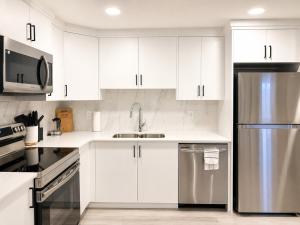 a kitchen with white cabinets and a stainless steel refrigerator at Modern 2BR Private Suite in SW Calgary in Calgary +6 photos