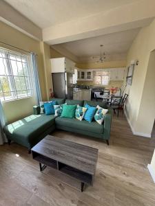 a living room with a green couch and a kitchen at Belle Cove in Gros Islet