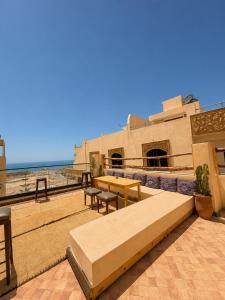 a patio with a table and benches and the beach at Kymata Surf Morocco in Agadir