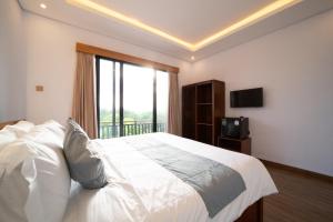 a bedroom with a large white bed with a window at Lunaire Guest House in Tabanan