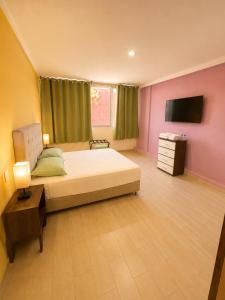 a large bedroom with a bed and a tv at Puul Suites in Mérida