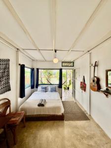 a bedroom with a bed and a guitar on the wall at Ban Narai River Guesthouse in Chiang Mai