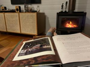 a person is reading a book in front of a fireplace at Mackerel Beach Wellness Lodge in Great Mackerel Beach