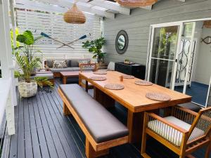 a patio with a wooden table and benches on a deck at Mackerel Beach Wellness Lodge in Great Mackerel Beach