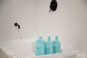 three bottles of soap in a shelf in a bathroom at Stylish Clontarf Townhouse & Parking in Clontarf