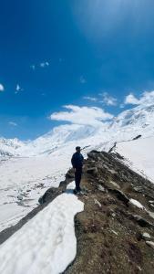 a man standing on top of a snow covered mountain at Minapin Nagar Tourist Lodge in Minapin