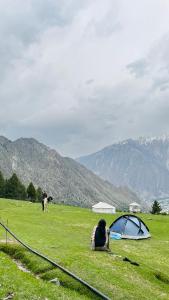 a person sitting in a field next to a tent at Minapin Nagar Tourist Lodge in Minapin