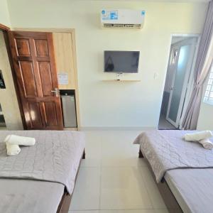 a room with two beds and a tv on the wall at Chu's Hotel & Homestay in Xã Thang Tam