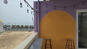 a purple and yellow wall with two stools and lights at Chu's Hotel & Homestay in Xã Thang Tam