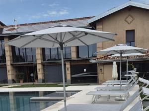 two white umbrellas and chairs next to a pool at Elegant suite with shared pool in Adro
