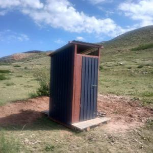 a outhouse sitting in the middle of a field at Актан in Chong-Kyzylsu