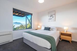 a bedroom with a large bed and a large window at Rosetta Vista - Architectural Haven with River Views in Berriedale