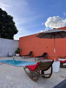 a bench and an umbrella next to a swimming pool at Suítes Brotas in Brotas