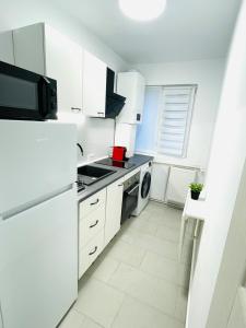 a white kitchen with a refrigerator and a dishwasher at MBZ Apartments #1 - 1 Bedroom, Private Parking & Air Conditioning in Roman