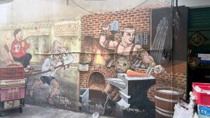 a mural on the side of a building with a man cooking in a oven at Four Sisters Hostel in Bangkok
