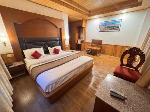 a bedroom with a large bed and a desk at Hotel The Red Apple in Manāli