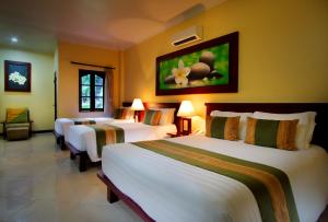 a hotel room with three beds in a room at Adi Dharma Hotel Kuta in Kuta
