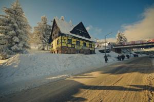 a building on the side of a snow covered road at Pensjonat Stokłos in Duszniki Zdrój