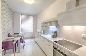une cuisine avec des placards blancs et une table avec des chaises violettes dans l'établissement Apartment Promenáda 35, à Karlovy Vary