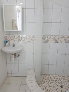 a white bathroom with a sink and a mirror at Evie Cottage in Bioche