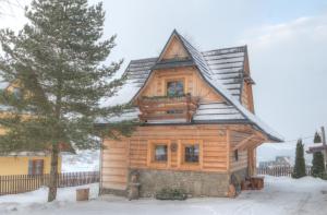 une cabane en rondins dans la neige avec un arbre dans l'établissement Góralski Domek z kominkiem - Highlander Wooden House, à Murzasichle