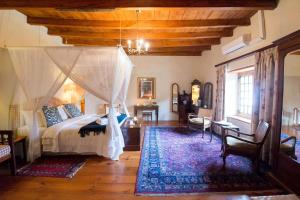 a bedroom with a canopy bed and a rug at Tulbagh Country Guest House - Cape Dutch Quarters in Tulbagh