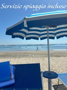 a blue chair and an umbrella on the beach at Apartament 2 bedroom with one bathroom and penthouse Apartament 3 bedroom and 2 bathroom included with umbrella and sunbeds in Lido Adriano