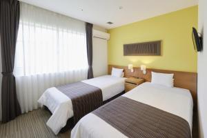 a hotel room with two beds and a window at Hotel Rotterdam Huis Ten Bosch in Sasebo
