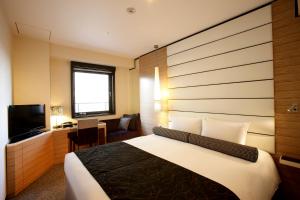 um quarto de hotel com uma cama e uma televisão em Hotel Trusty Osaka Abeno em Osaka