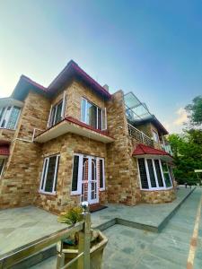 a large brick house with a balcony in front of it at Voyager stone cottage in Bhīm Tāl