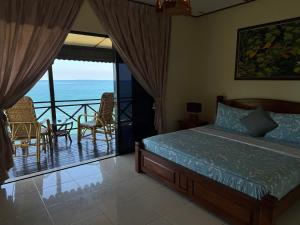 a bedroom with a bed and a balcony with the ocean at Minang Cove Resort in Tioman Island