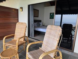 a balcony with two chairs and a bed and a bed at Minang Cove Resort in Tioman Island