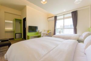 ein Hotelzimmer mit zwei Betten und einem Fernseher in der Unterkunft Pandora B&B in Taitung