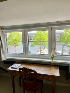 a table in a room with three windows at Private attic room with workspace & water view in Haarlem