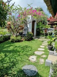 a garden with a stone pathway and pink flowers at Murnis Bungalow in Lovina