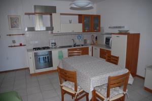 una cocina con mesa y sillas y una cocina con electrodomésticos blancos. en Love & Live Pinè, en Baselga di Pinè