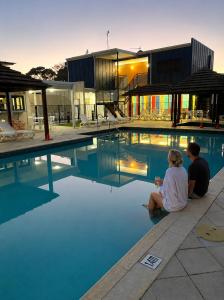 a man and woman sitting next to a swimming pool at Townhouse 7 - Located at FOOTPRINTS PRESTON BEACH RESORT in Preston Beach