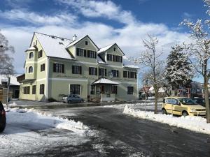 Une grande maison blanche dans la neige dans une rue dans l'établissement Gasthof Wagner Restaurant-Pension, à Halbenrain