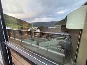 a window with a view of a balcony with a couch at Aurora Apartments - Mountain View in Stryn +27 photos